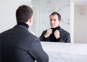 Multiple shots of someone looking at their reflection in a bathroom mirror with marble walls.