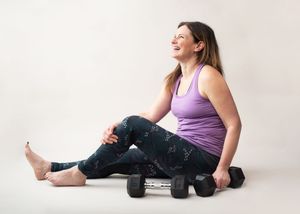 A person in purple athletic wear demonstrates a seated yoga stretching sequence on a white background.