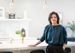 Professional portrait series of a woman in a navy blue top sitting on a modern couch in a bright interior setting.