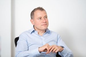 Professional wearing a light blue button-down shirt sits in contemplative poses against white background.