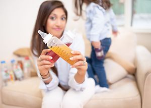 A person holds a fresh waffle cone with soft serve ice cream against a light background.