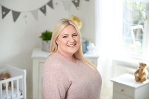 A bright and airy nursery room decorated with grey bunting flags and white furniture.