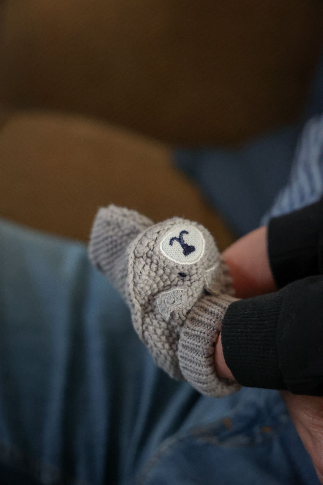 Close-up of knitted gray fingerless gloves with cute animal face details.