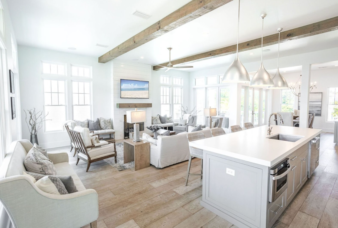 Modern open concept apartment interior with exposed wooden beams, white walls and contemporary furnishings in natural light.