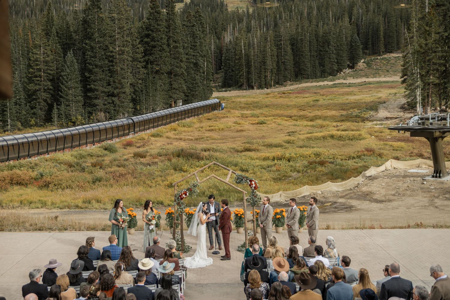 A panoramic sequence of people gathering near a scenic mountain forest area with parked vehicles and guard rails.