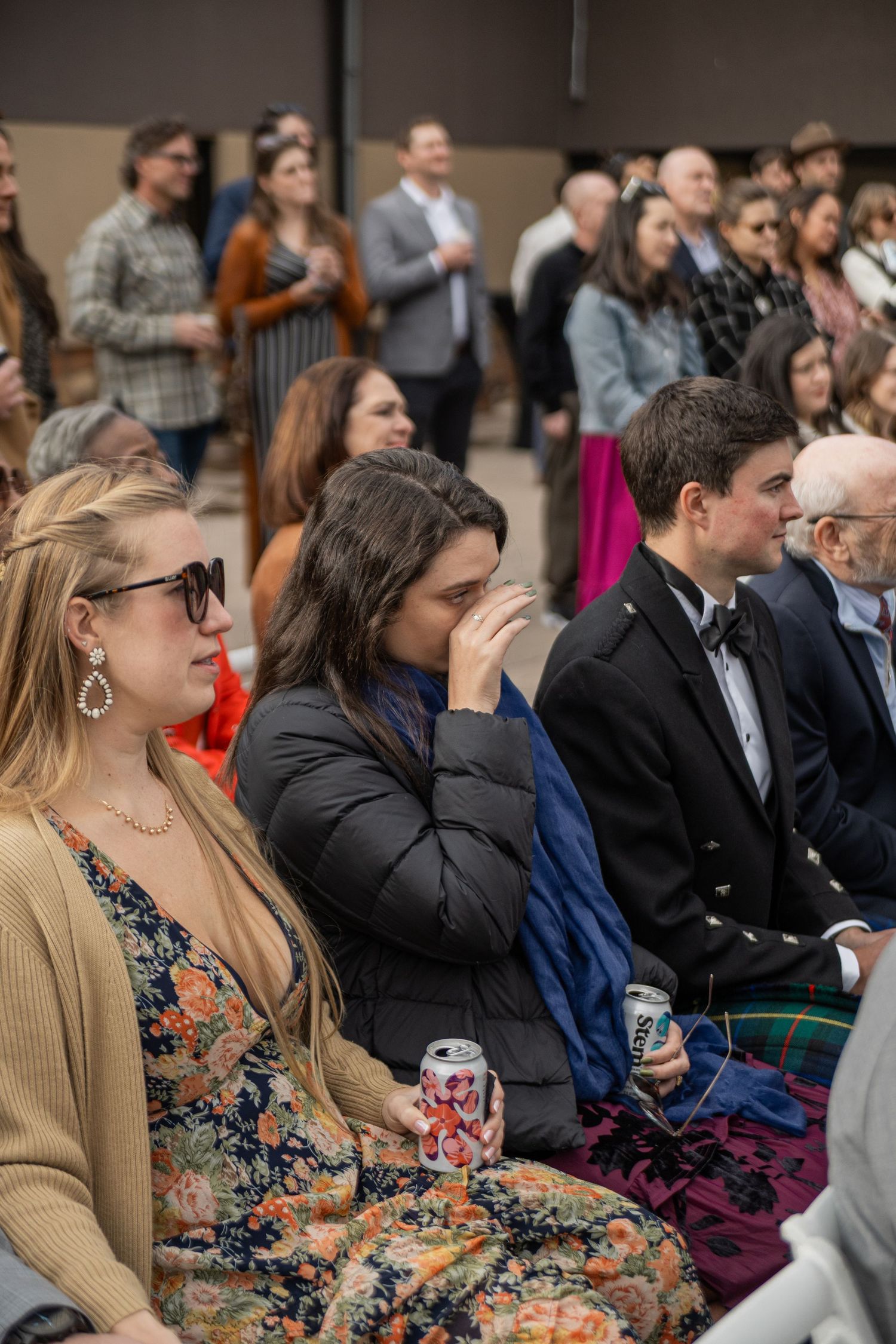 Audience members seated in rows attentively watch a presentation or performance in an indoor venue.