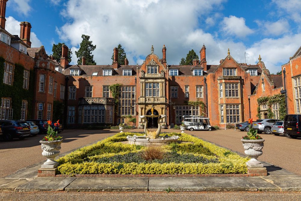 Historic English manor house Tylney Hall with Tudor architecture and ornate garden courtyard featuring a central fountain and landscaping.