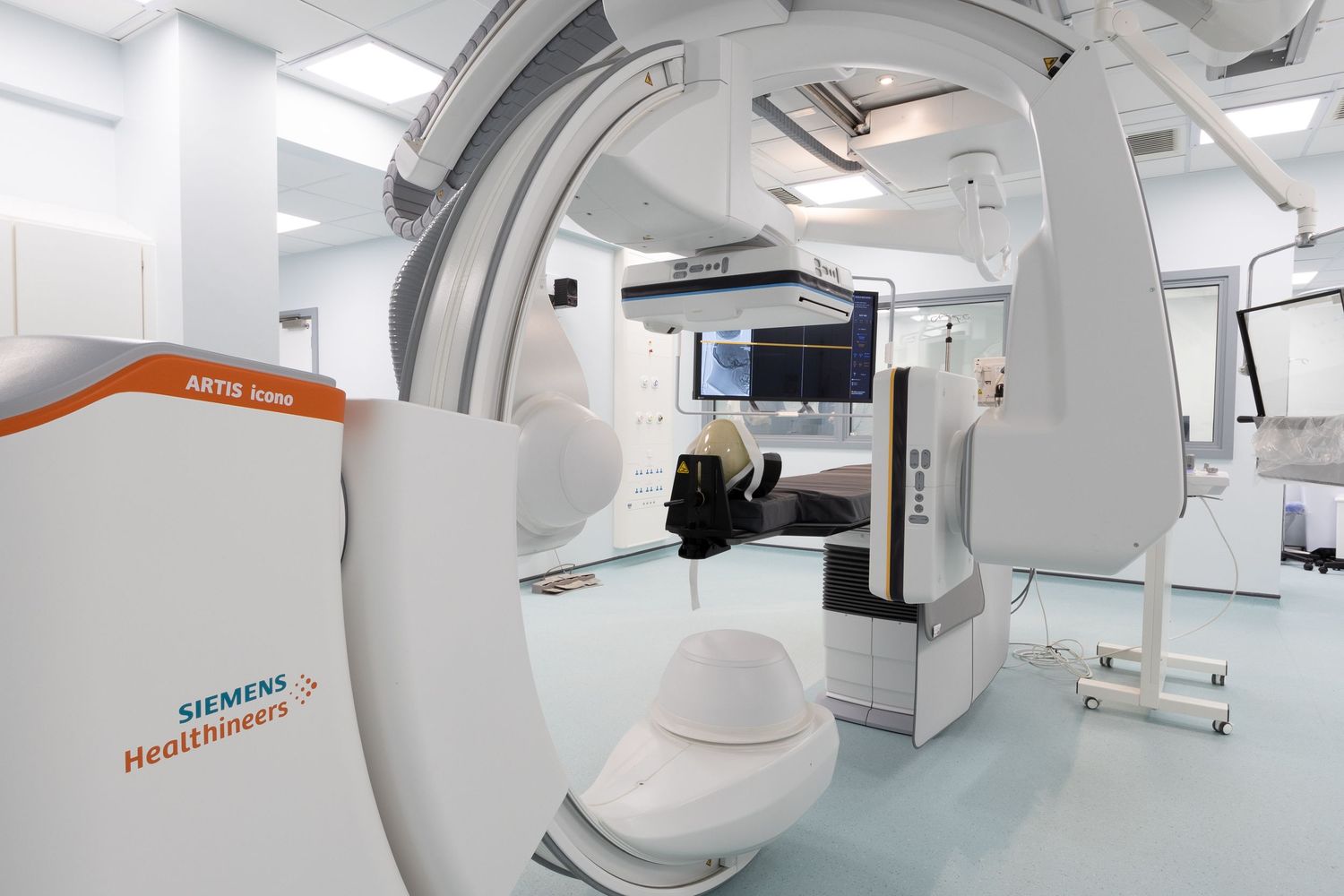 Modern medical imaging room with advanced angiography equipment and monitors in a bright clinical setting.