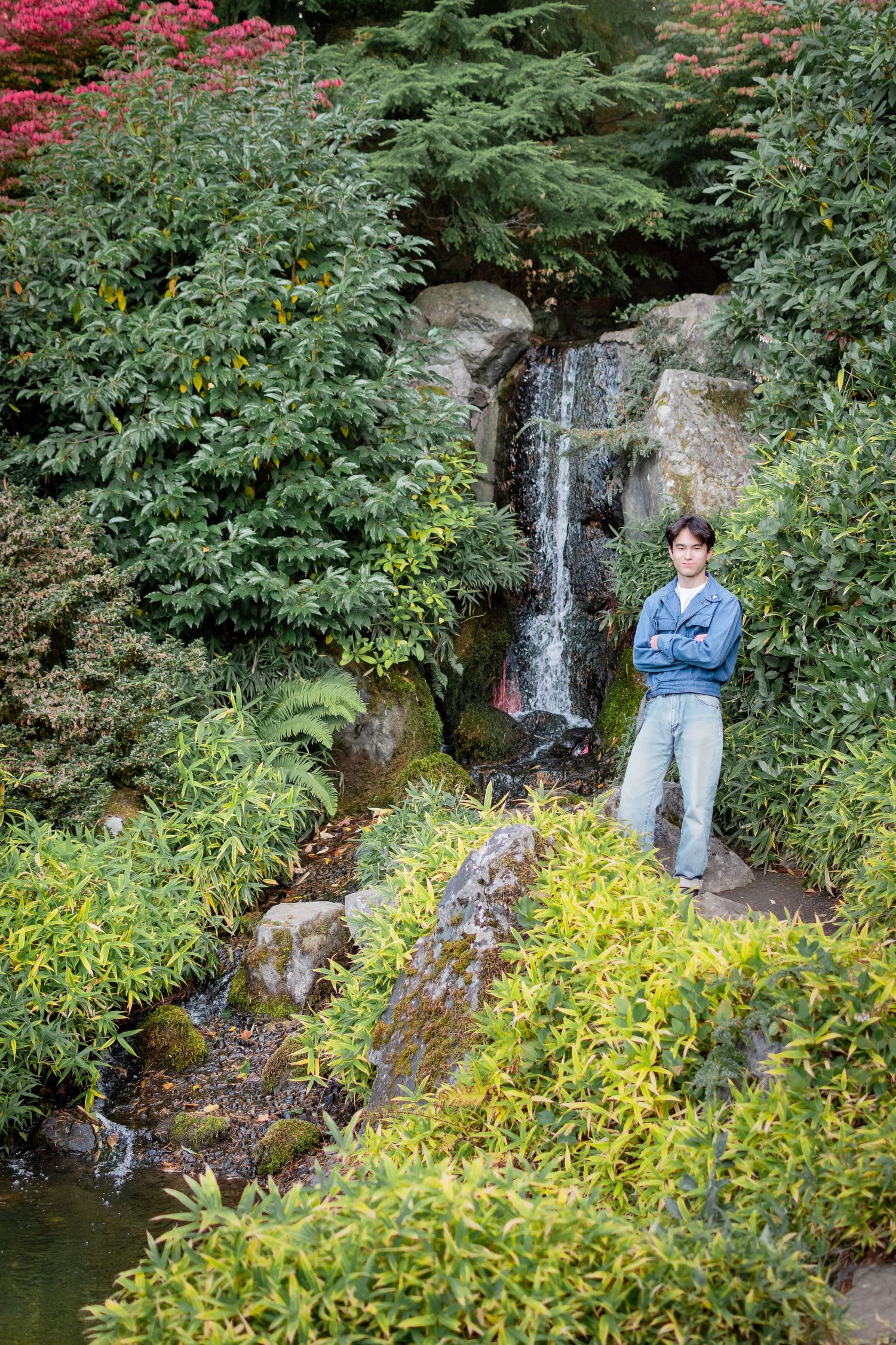 Senior portrait of a teen boy posing at the waterfall area in Kubota Garden in Seattle.