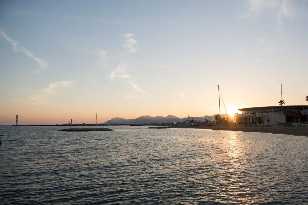 Golden sunset over a quiet harbour with calm water and silhouetted boats.