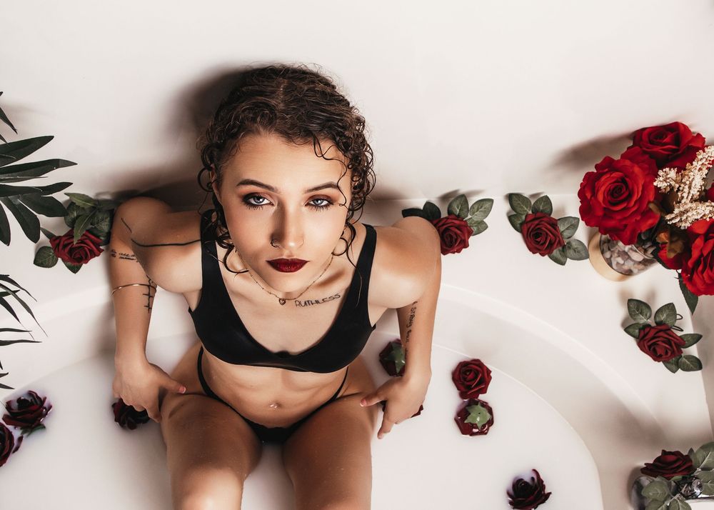 A sensual boudoir photo series with red roses and black lingerie against a white backdrop.