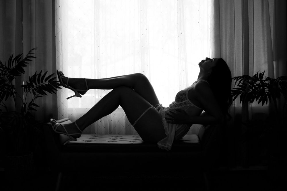 Silhouetted figure appears in dramatic black and white scene with dark shadows and contrasting light through window.