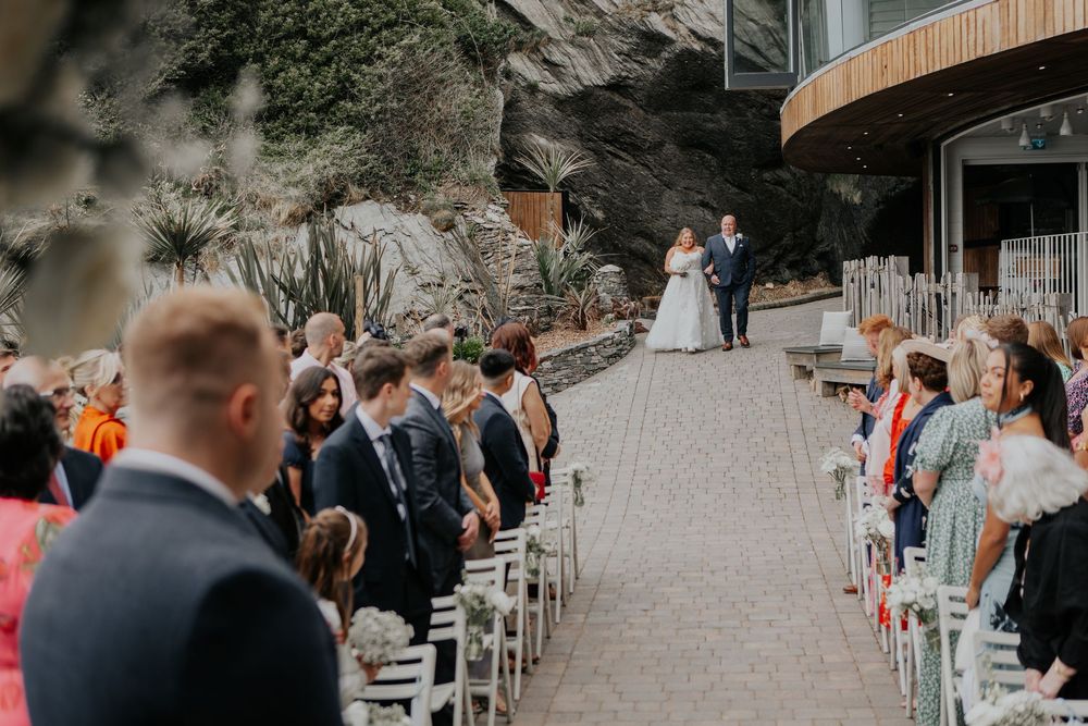 A bride and groom stand at the altar during an outdoor cliff-side wedding ceremony with guests.