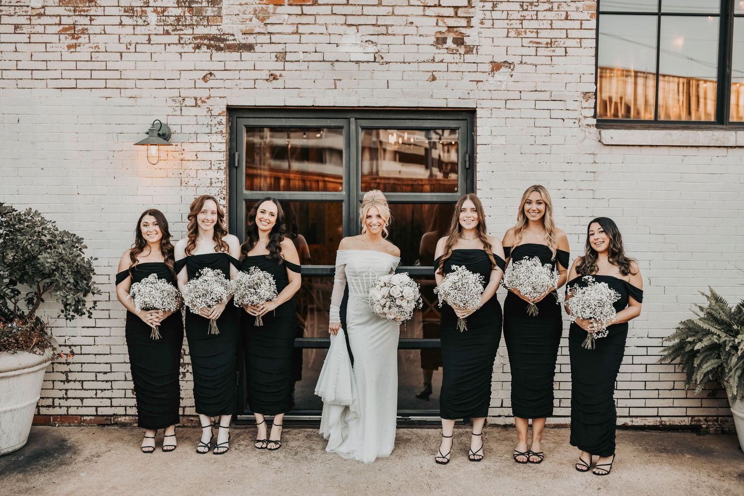 Candid groomsmen and bridesmaids celebrating at sunset, warm light and industrial textures creating a modern Dallas aesthetic.