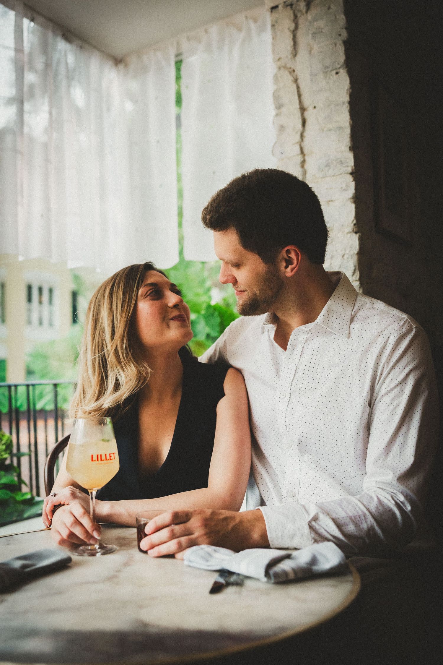 A couple shares an intimate moment while sitting together at a table in a dimly lit restaurant.
