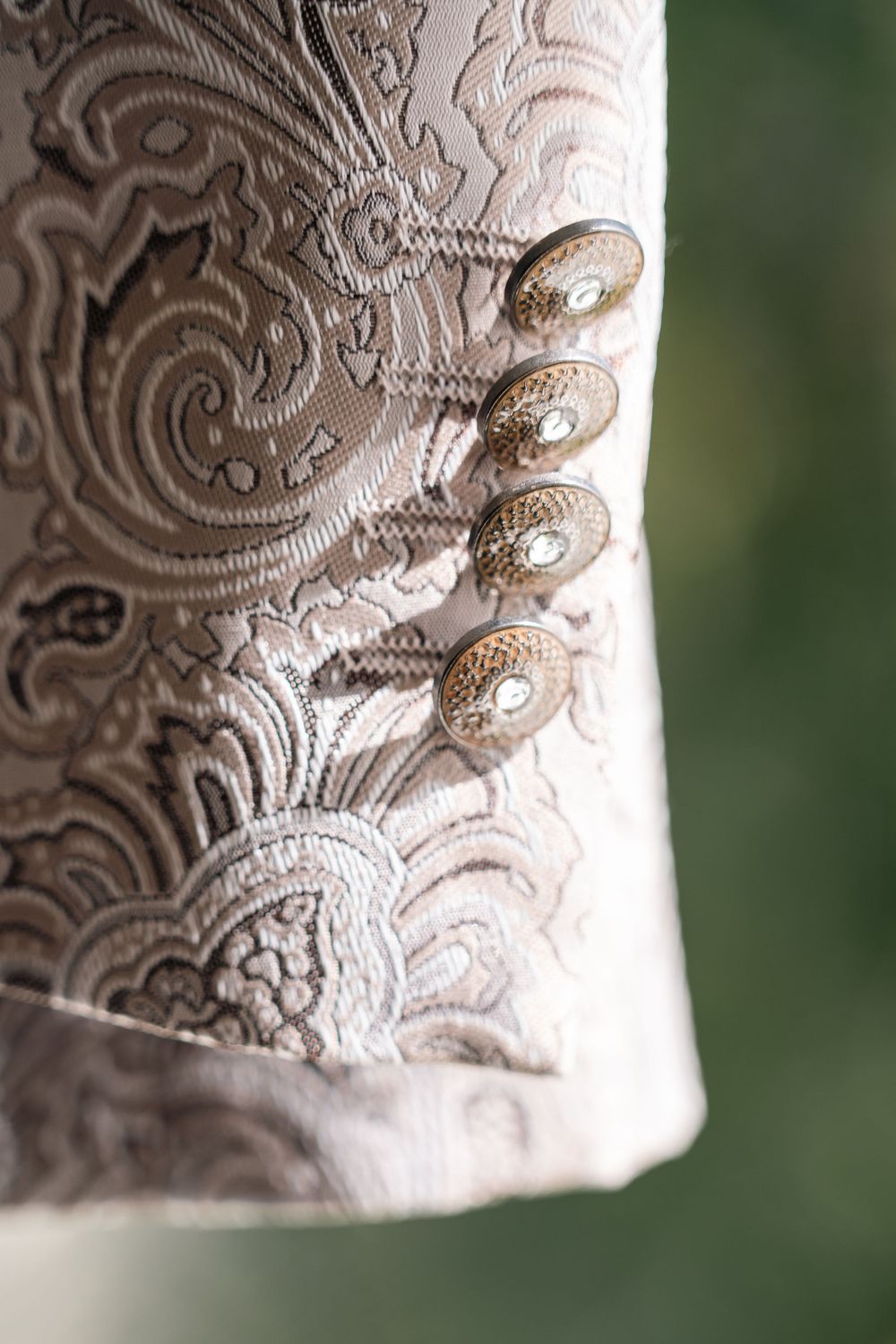Close-up detail of intricate white lace embroidery pattern on formal attire.