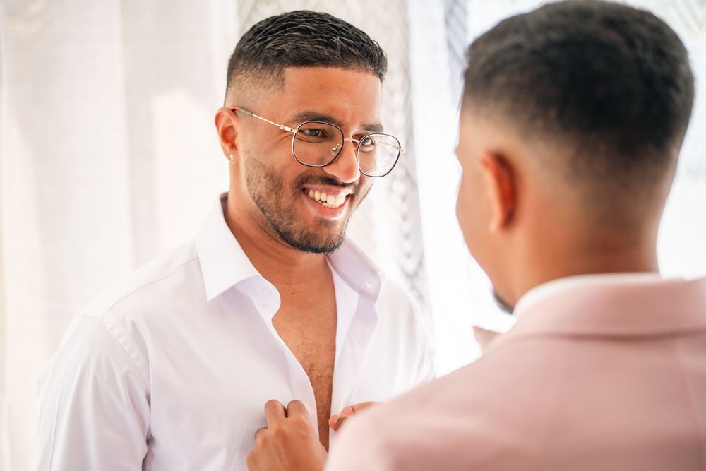 Wedding party members in crisp white attire share a candid moment.