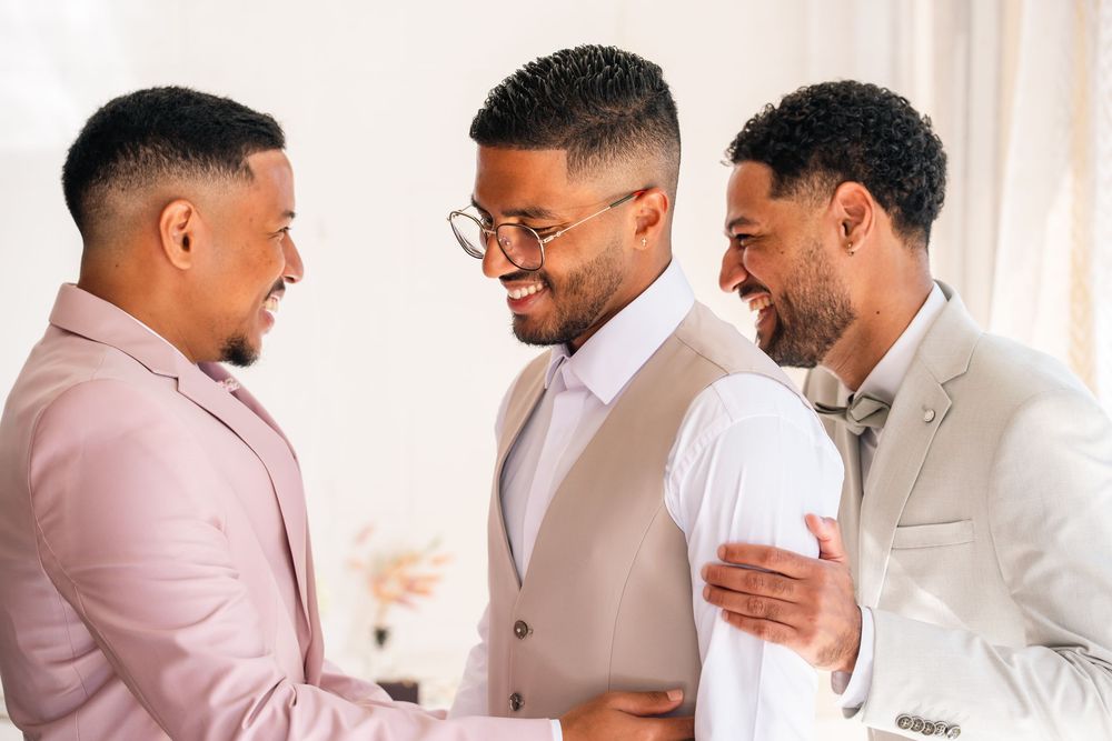 A group of people in formal attire embrace and congratulate each other in a bright indoor setting.