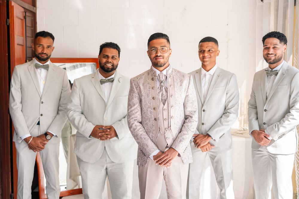 Wedding party members lined up in elegant white suits for a formal group photo.