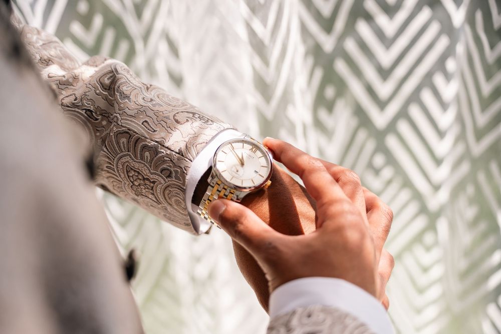 Wedding details showing hands holding rings and bouquets against a chevron patterned background.