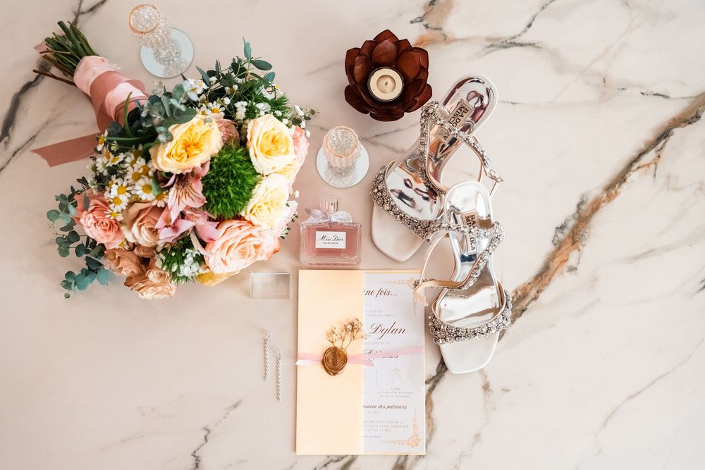 Wedding detail flatlay with floral arrangements and stationery on marble surface.