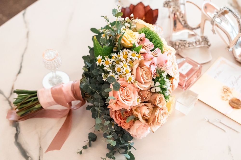 Delicate peach and coral roses arranged in a romantic wedding bouquet with greenery.