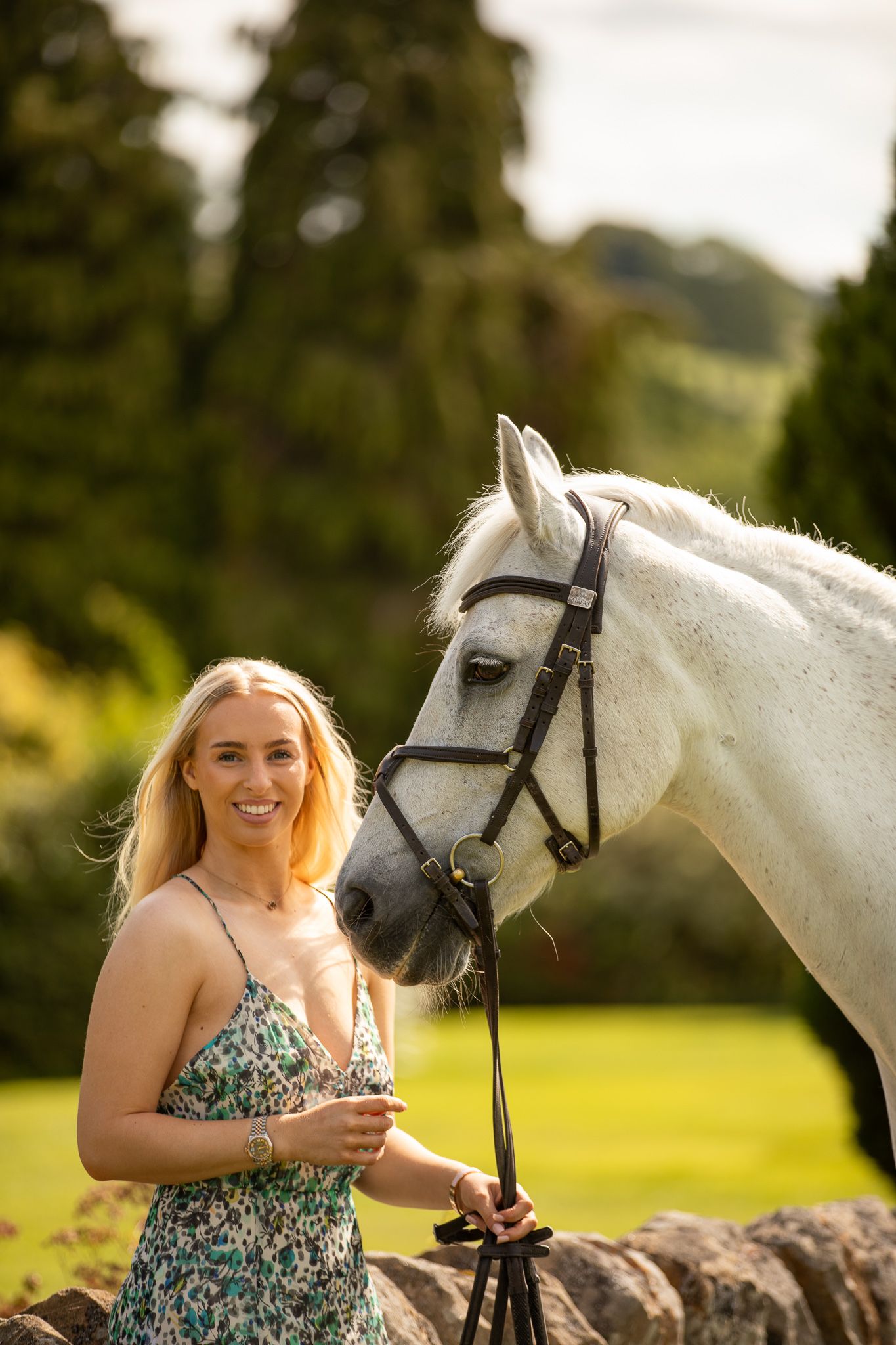Young girl in denim overalls embraces a palomino horse in a sun-dappled forest setting.