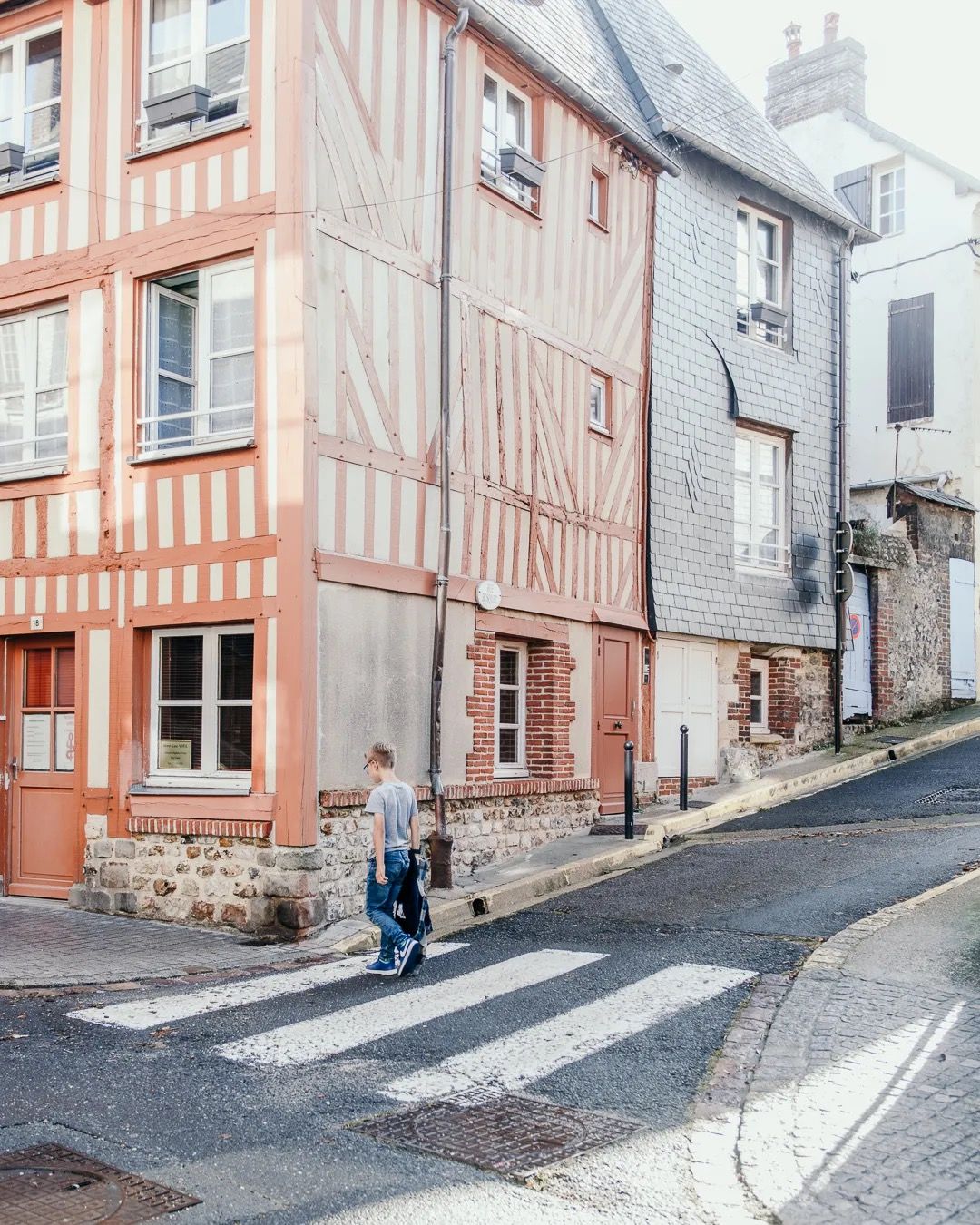 Narrow cobbled street lined with pastel French houses and soft afternoon light.