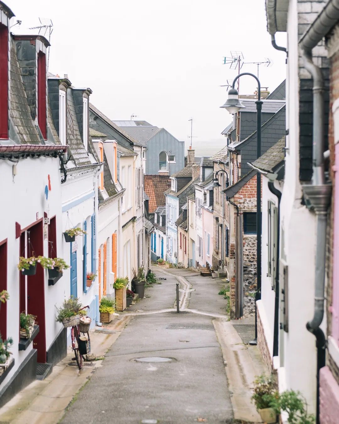 Narrow cobbled street lined with colourful houses in a quiet European village.
