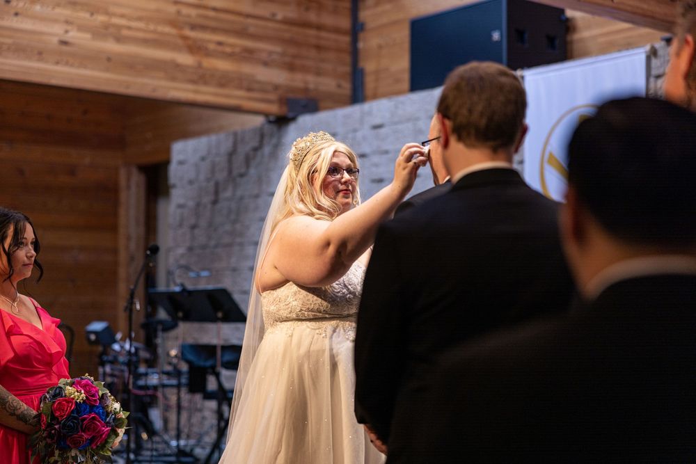 Wedding party celebrates with dancing and laughter in a rustic wooden barn venue.