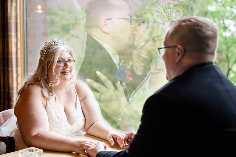 Bride and groom share joyful laughter during their wedding reception at a sunlit venue.