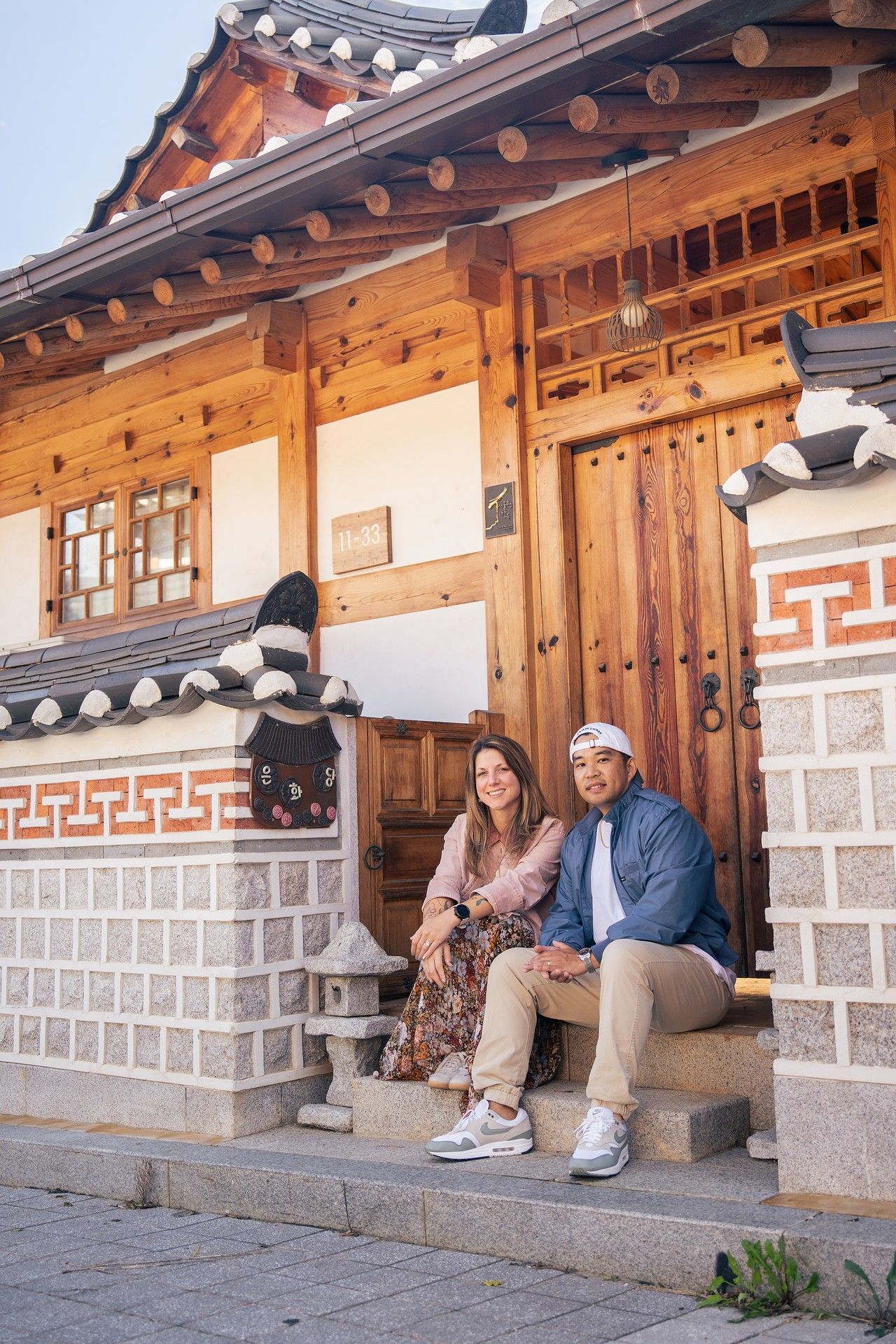 Traditional Korean hanok house exterior with wooden architecture and tiled roof in sunlit courtyard setting.
