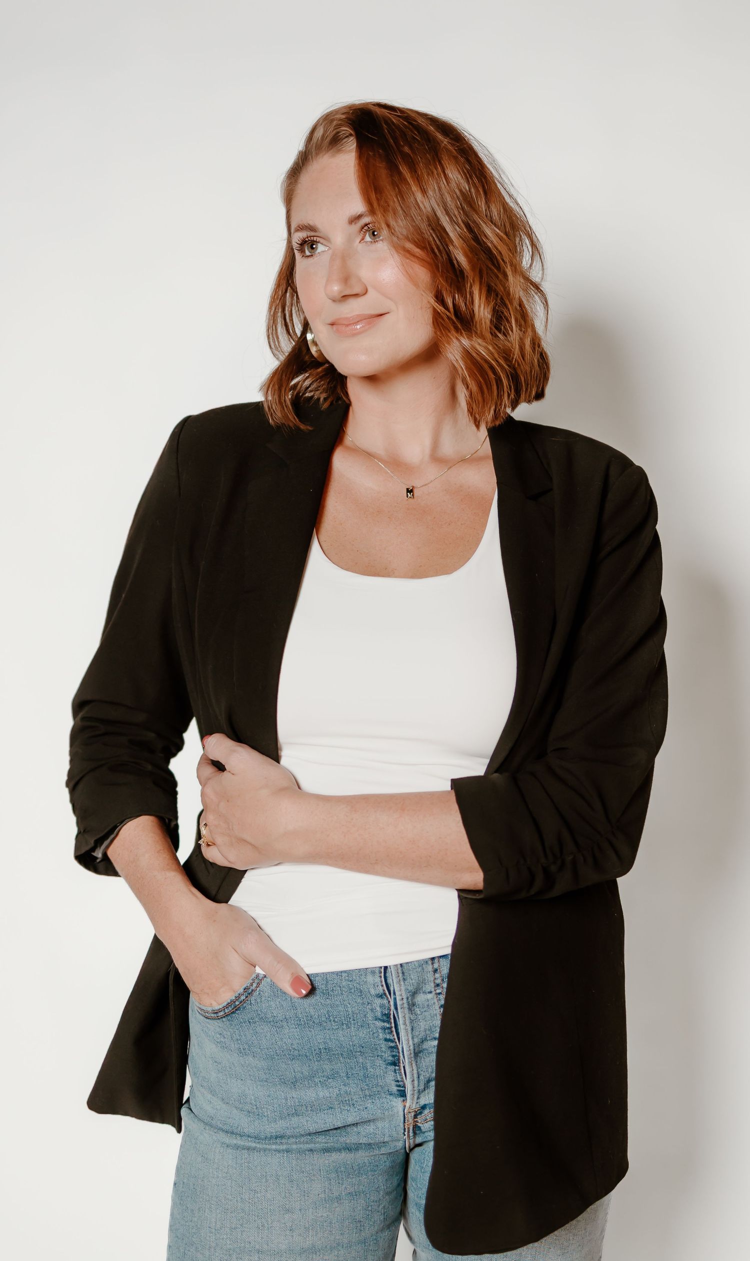 Woman in black blazer and jeans posing against white background in various casual poses.