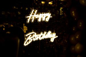 Illuminated 'Happy Birthday' neon sign glowing in the dark.