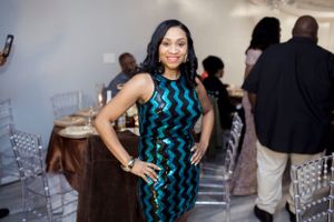 Woman in blue and black patterned dress posing at formal event.