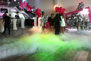 Atmospheric party scene with green fog effect and red balloons creating a festive ambiance.