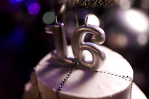 Close-up of silver number 16 candle on top of birthday cake.