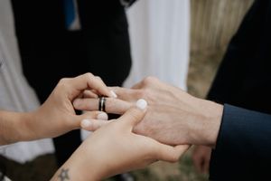 Close-up of hands exchanging wedding rings during ceremony.