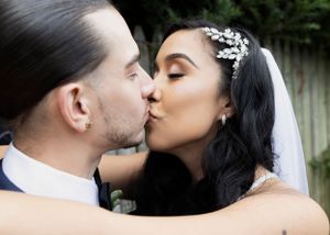 A romantic kiss shared between newlyweds during a wedding ceremony, with the bride wearing a delicate crystal hairpiece.