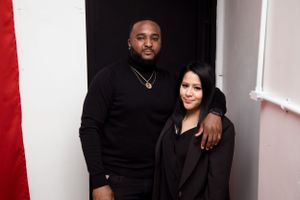 Couple posing together against a white and red wall at a formal event.
