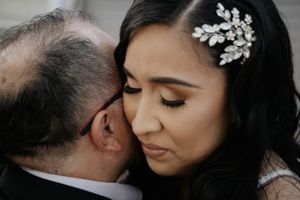 An emotional moment captured during a wedding as the bride receives a loving kiss on her cheek.