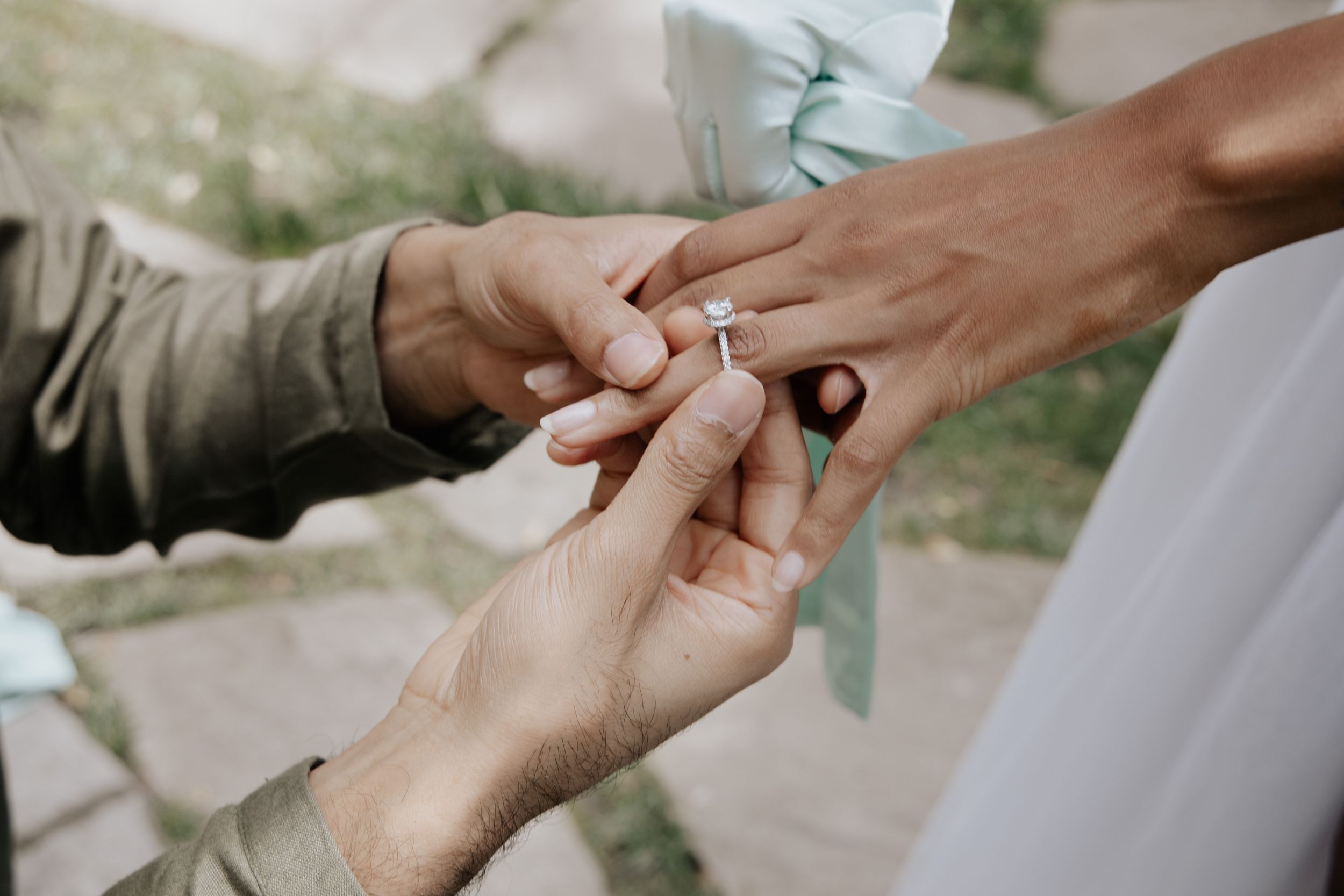 Close-up shot of hands exchanging an engagement ring during a proposal moment.
