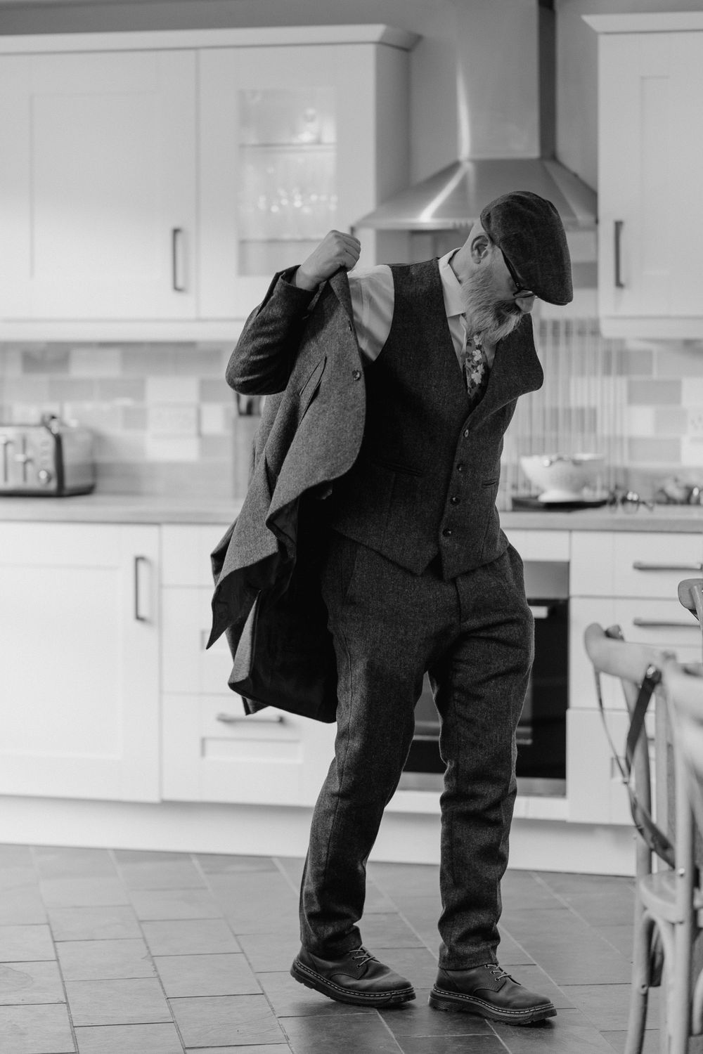 Father of the groom is putting his suit jacket on.