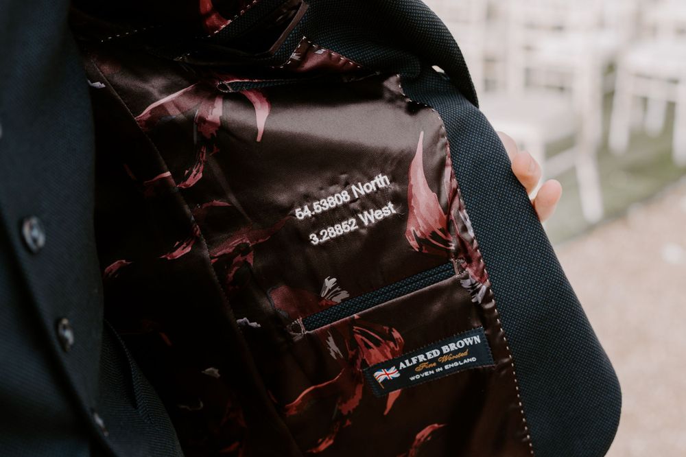A close up of the inside of the grooms suit jacket. Embroidered inside is the coordinates onto where he proposed to his wife to be.
