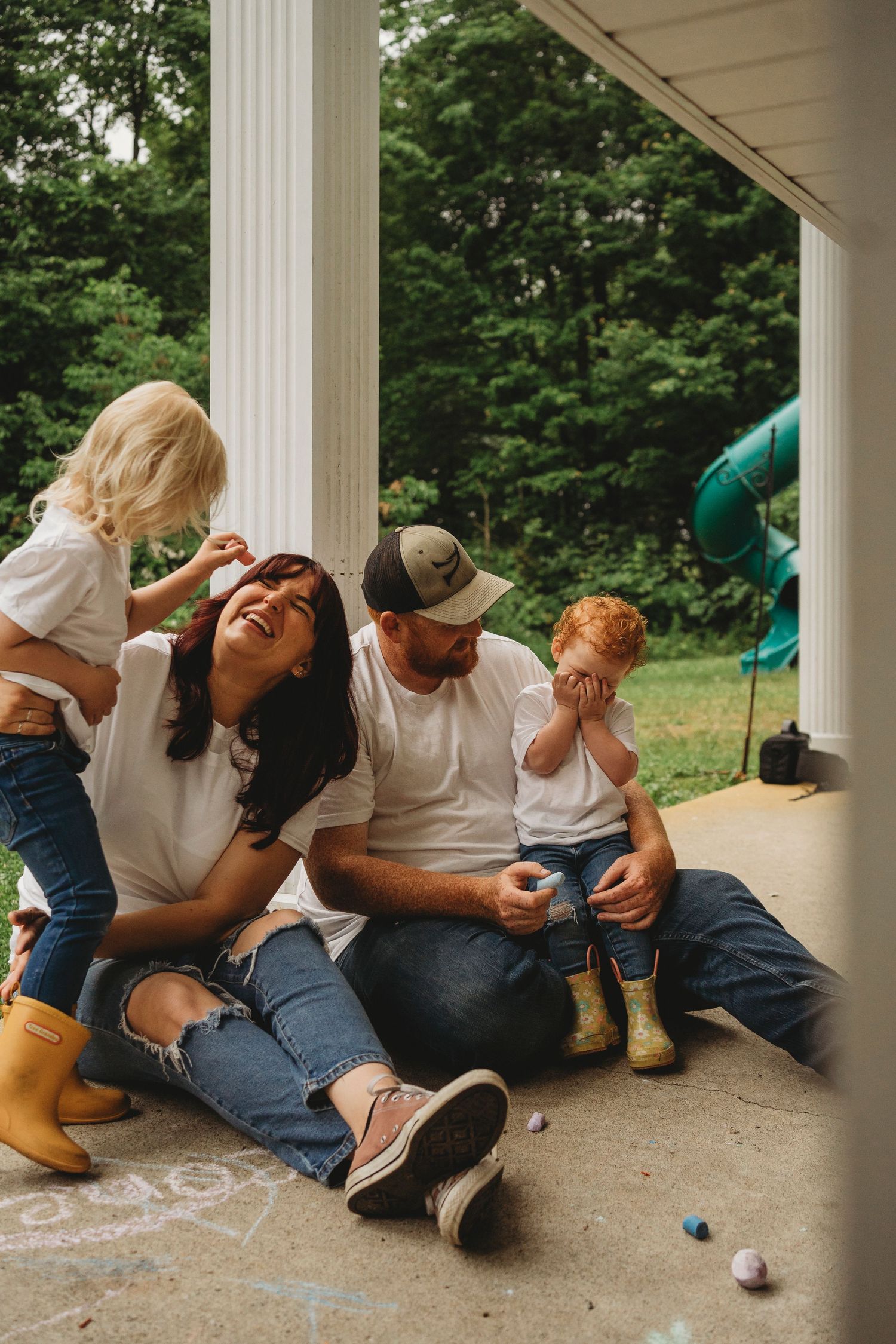 Playful family moment on a porch with yellow rain boots.