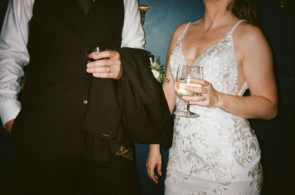 A couple holding champagne glasses, with focus on formal wedding attire.