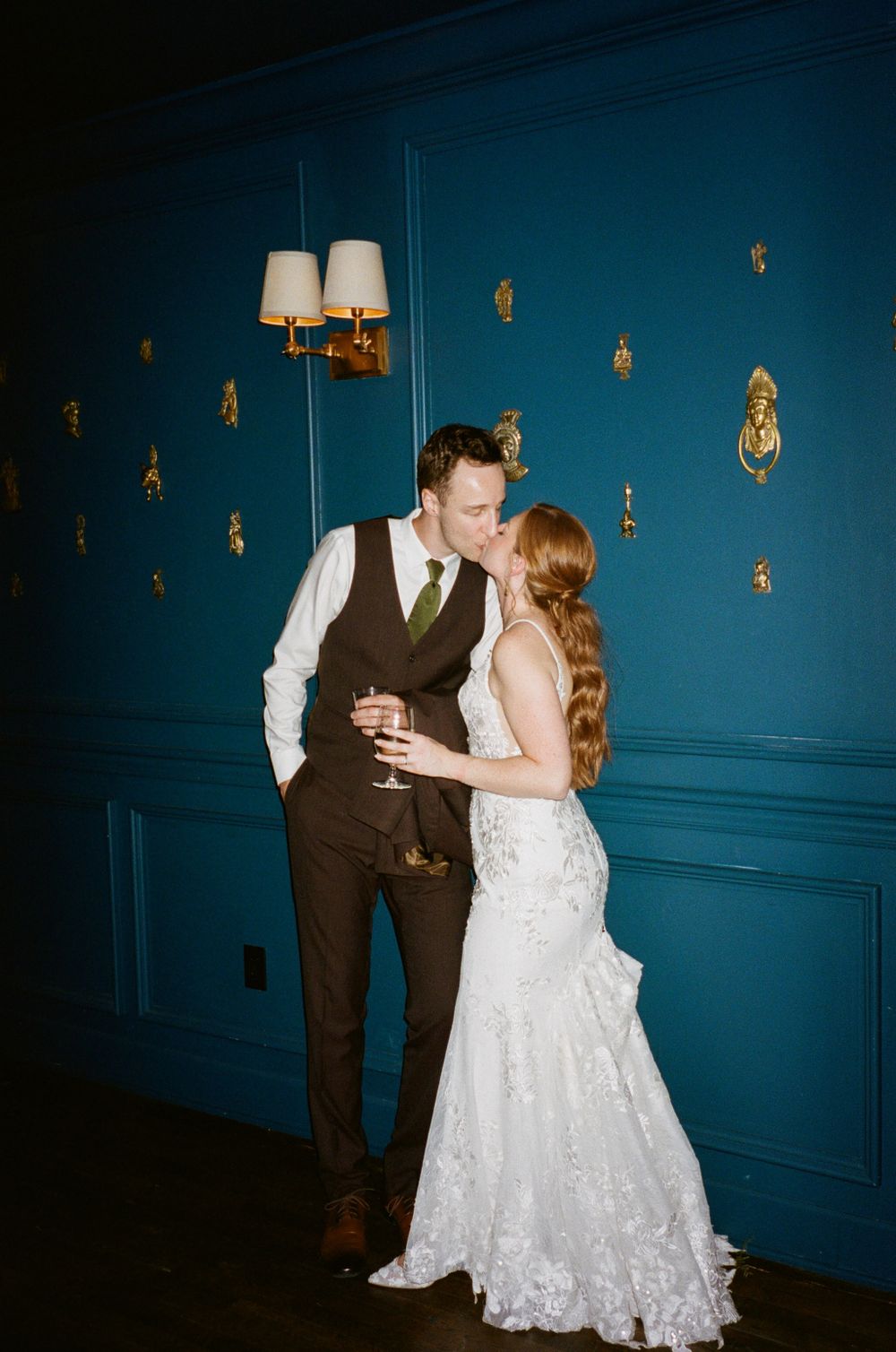 A romantic moment between a couple against a blue wall with decorative gold accents.