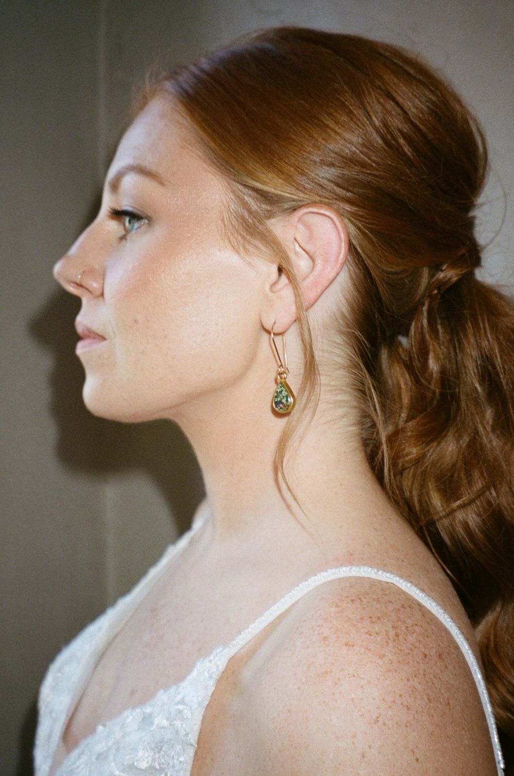 Profile view showing an elegant bridal hairstyle and delicate earring.