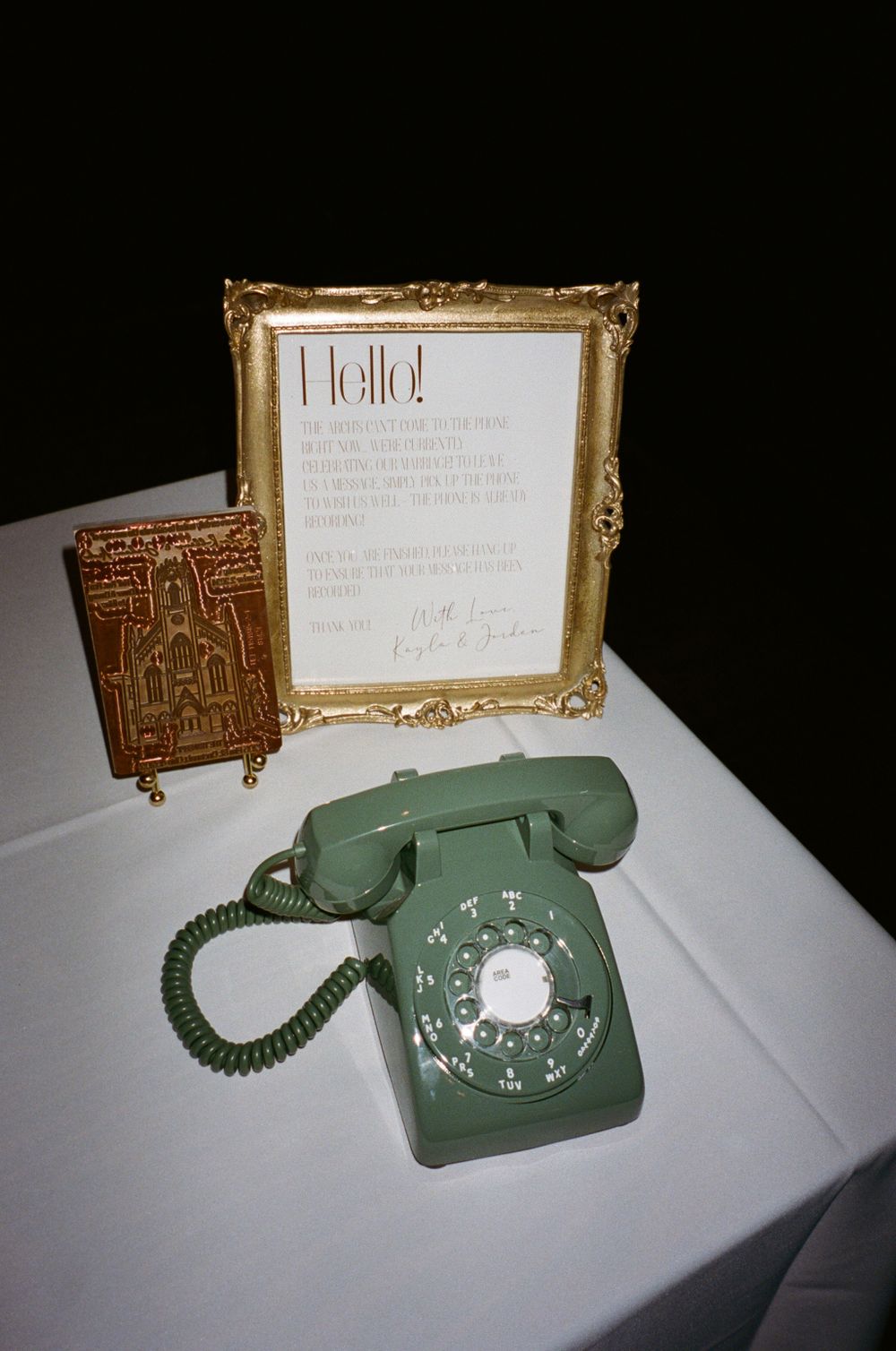 Vintage rotary phone in sage green next to a framed welcome sign.