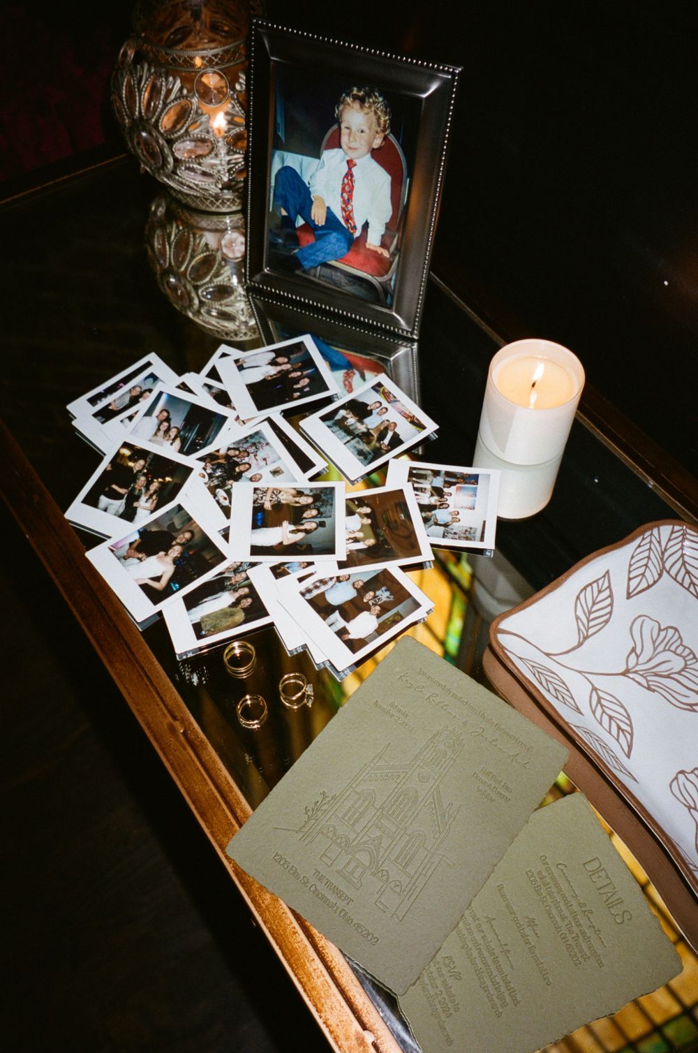 Wedding reception table with polaroid photos, candle, and framed picture display.